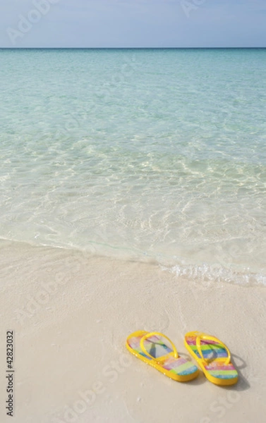 Obraz A PAIR OF FLIP FLOPS AT THE BEACH COVERED WITH SAND