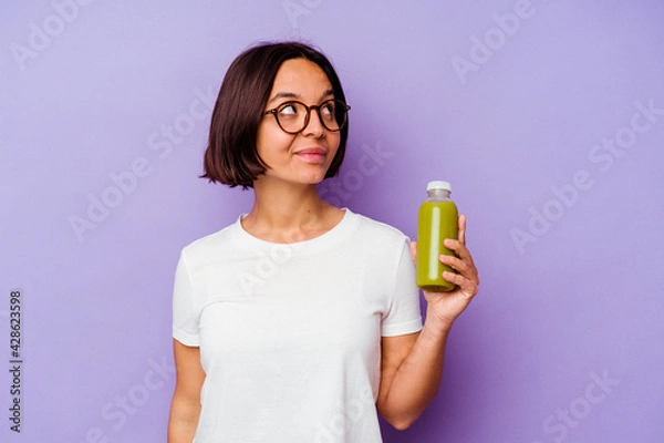 Obraz Young mixed race woman holding a healthy smoothie isolated on purple background dreaming of achieving goals and purposes