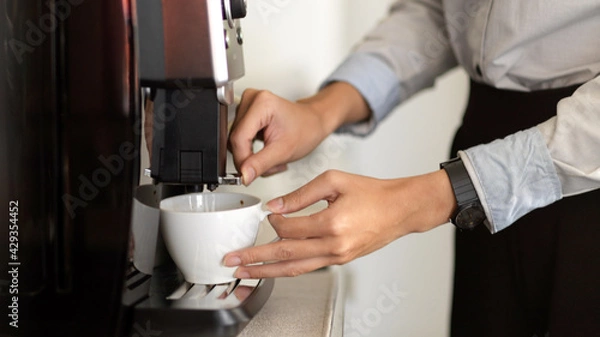 Fototapeta Female office worker hands making a coffee with coffee machine in office cafeteria