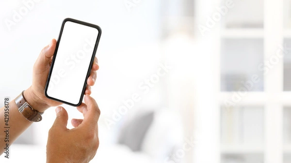 Fototapeta Hand man holding blank screen mock up smartphone with blurred background