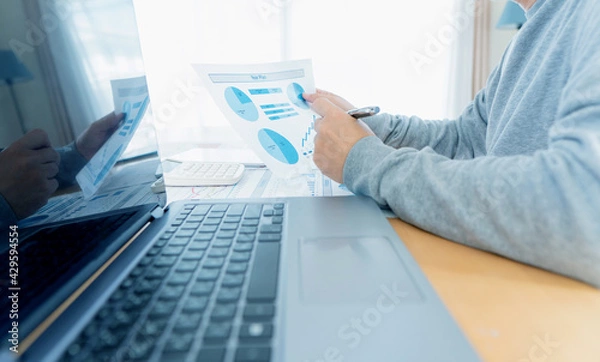 Fototapeta Businessman hand analyzing chart on paper investment charts with laptop. Accounting. Business concept