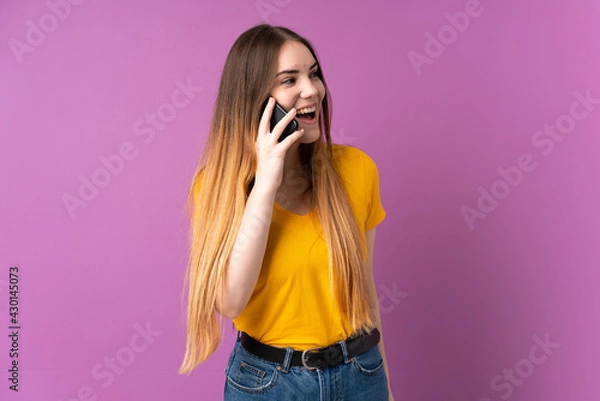 Fototapeta Young caucasian woman isolated on purple background keeping a conversation with the mobile phone