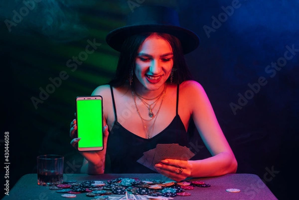 Fototapeta online poker player with a smartphone at a casino table with cards and chips