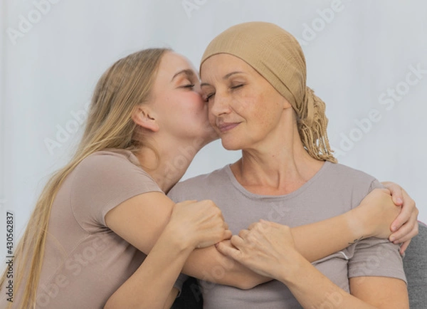 Fototapeta A young and beautiful daughter kiss her mother cancer patient and fortifies her to fight during the chemotherapy. Concept for love and support from beloved and family to breast cancer people