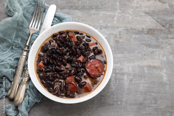 Fototapeta black beans with meat and sausages in white bowl