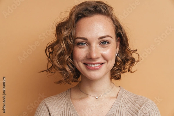 Fototapeta Young ginger woman with wavy hair smiling and looking at camera