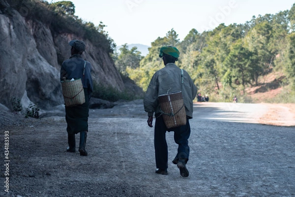 Fototapeta Two local burmese men walk down a gravel road, Myanmar