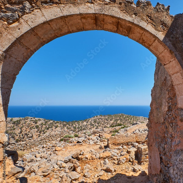 Fototapeta An roman Arch of an ruin facing a cliff of the mediterranean sea with vegetation on it