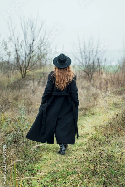 Fototapeta Portrait of young attractive woman in black coat and hat.