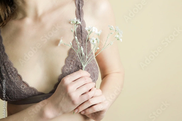 Fototapeta Female in lace bra holding flower. Prevention of breast diseases, woman health and self care concept.