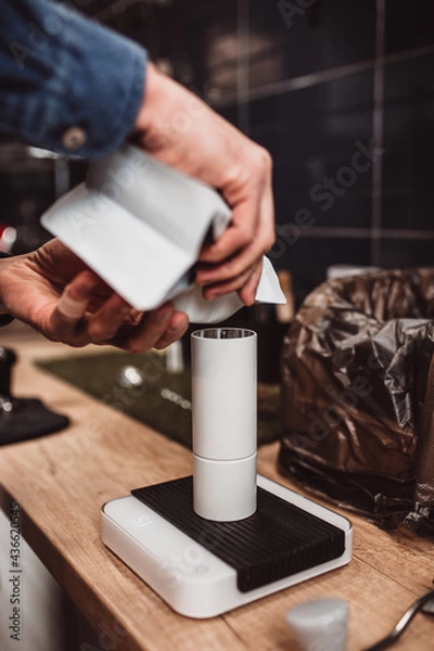 Fototapeta Barista grinds coffee beans in a hand mill