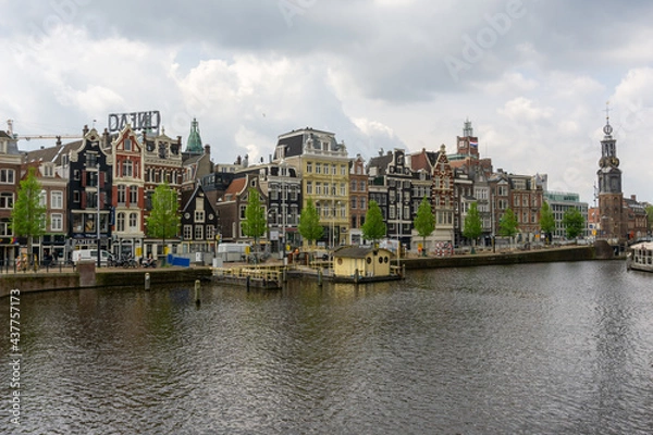 Fototapeta cityscape view of Amsterdam with many historic buildings lining the sides of the Amstel canal