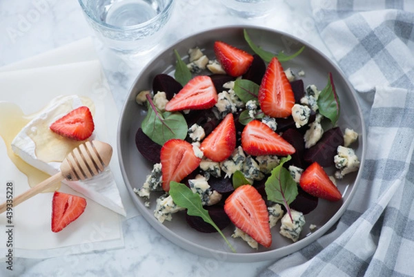 Fototapeta Plate with beetroot, strawberry and gorgonzola cheese salad on a light-grey marble background, horizontal shot