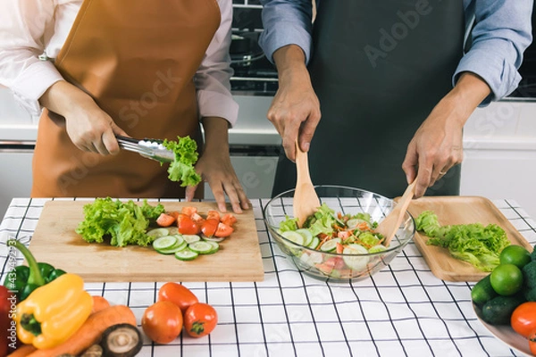 Fototapeta Asian couple enjoying cooking vegetable salad in the kitchen.