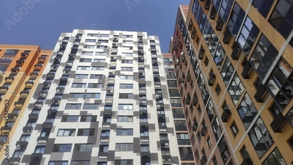 Fototapeta Multi-colored multi-storey new buildings with apartments against the blue sky in summer on a sunny bright day with beautiful bright facades with windows and glass