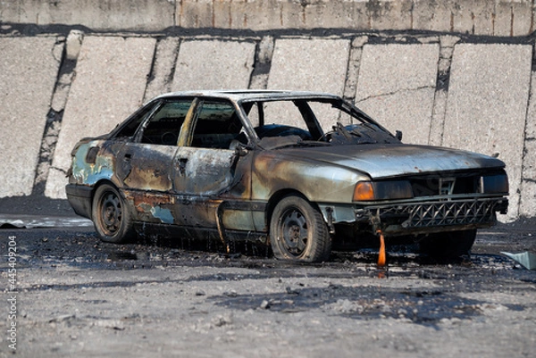 Fototapeta Abandoned and burnt out car. An abandoned burnt car left on the side of a quiet country road.