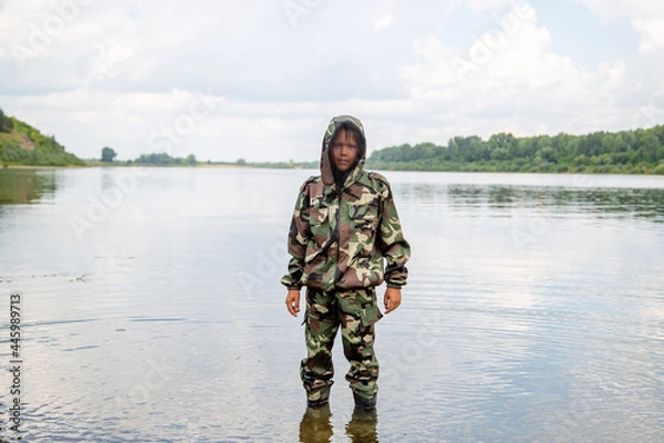 Fototapeta guy fisherman in a khaki suit with a mosquito net on the river