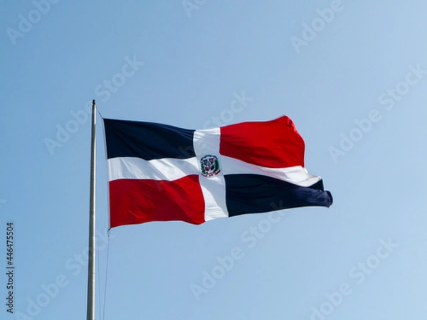 Fototapeta The Dominican flags waving with blue sky in the background