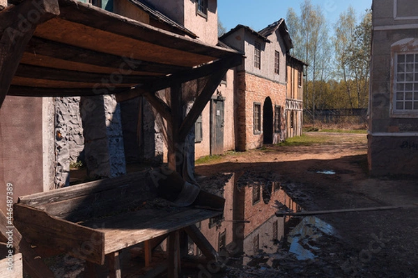 Fototapeta A puddle and a shopboard in front of 18th century houses against a sky in the piligrim porto by spring day