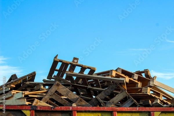 Fototapeta Old scrapped wooden shipping pallets in a randomly pile. Dumpster. Garbage removal