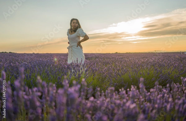 Fototapeta outdoors romantic portrait of young happy and attractive woman in white summer dress enjoying carefree at beautiful lavender flowers field in travel and holiday concept