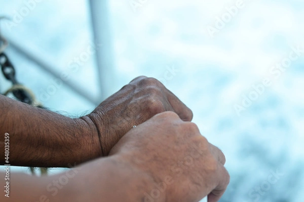 Fototapeta Two swarthy male hands on the handrail of the motor ship, blurred background