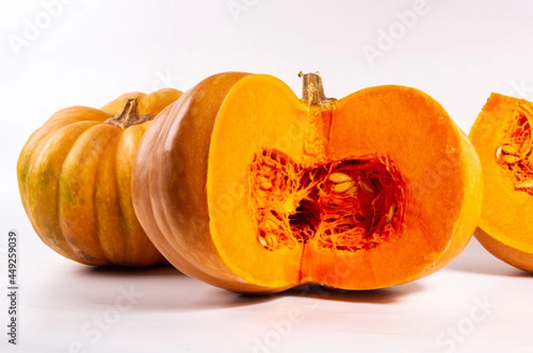 Fototapeta Whole fresh orange big pumpkin and slice of pumpkin on white background, closeup. Organic agricultural product, ingredients for cooking, healthy food vegan.