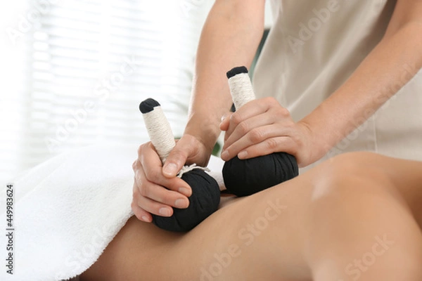 Fototapeta Young woman receiving herbal bag massage in spa salon, closeup