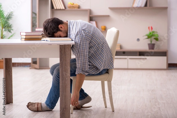 Fototapeta Young male student preparing for exams at home