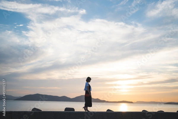 Fototapeta 夕暮れの海にいる女性