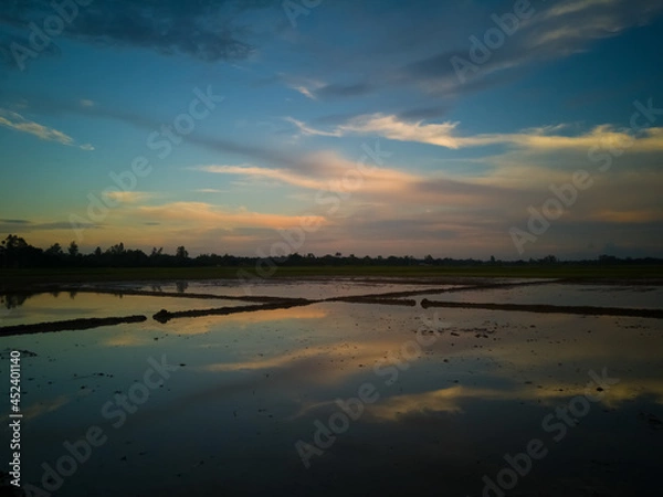 Fototapeta An Unique And Rare Natural Scenery Of Bangladesh With Colourful Clouds On Sky And The Reflection Of Colourful Clouds On Muddy Water Land. 