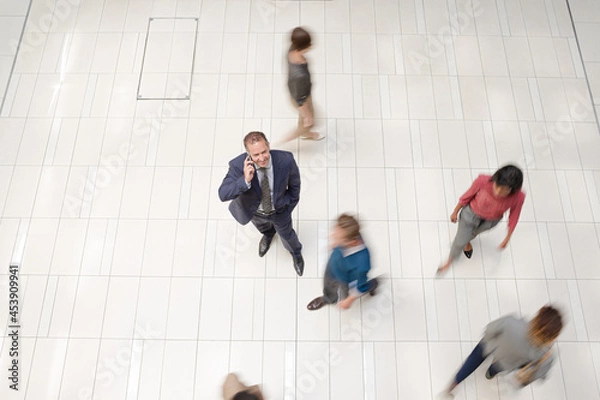 Obraz Businessman smiling in busy office hallway