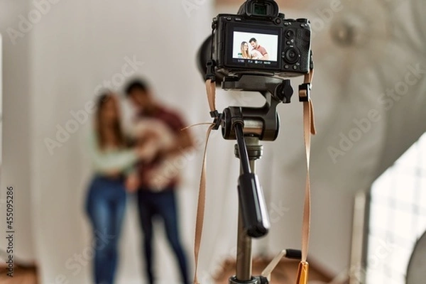 Fototapeta Professional camera taking photo of beautiful couple with dog at photography studio.