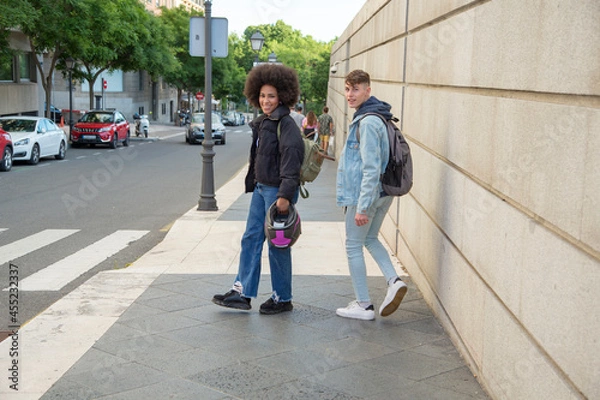 Fototapeta African American woman and Caucasian man walking through the city with a motorcycle helmet in hand