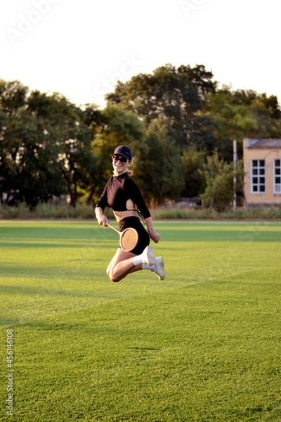 Fototapeta Young beautiful girl on the football field with a tennis racket 