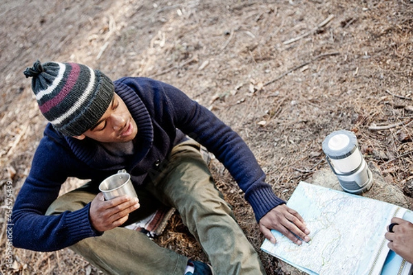 Fototapeta Young man with mug, looking at map outdoors