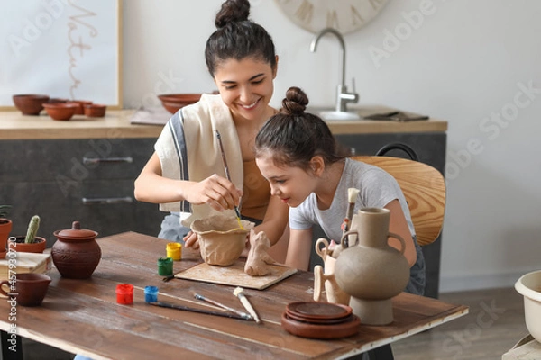 Fototapeta Little girl with her mother painting ceramic pot at home