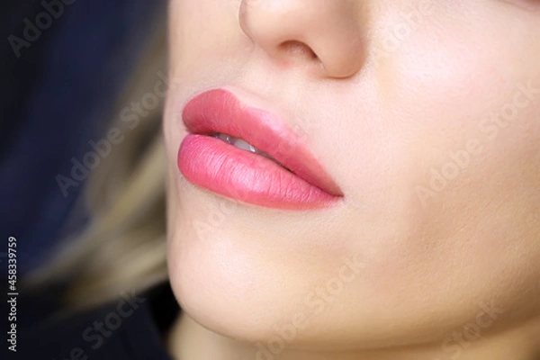 Fototapeta close-up of the beautiful lips of a young model with a lip tattoo