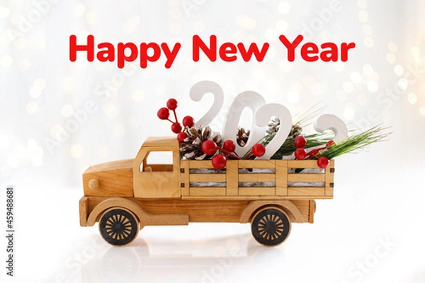 Fototapeta Happy New Year 2022. Wooden toy car with with berries and cones. Creative concept for new year greeting card. Happy new year text.