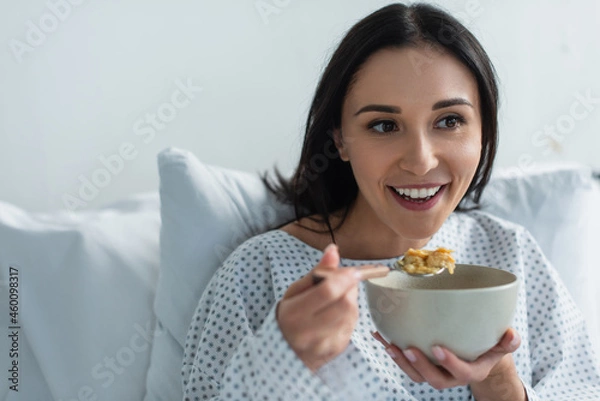 Fototapeta smiling patient holding spoon with corn flakes and bowl in hospital