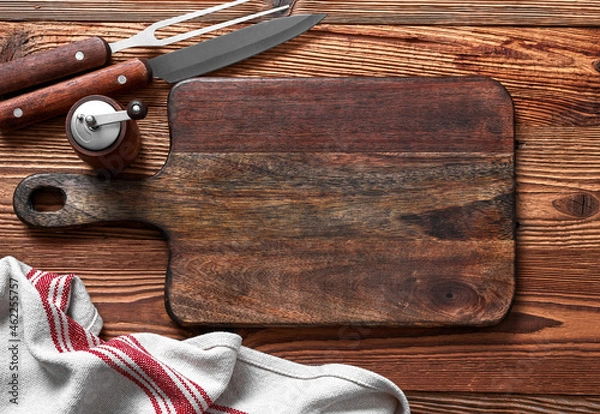 Fototapeta Empty cutting board, salt and pepper, fork and knife on a wood table