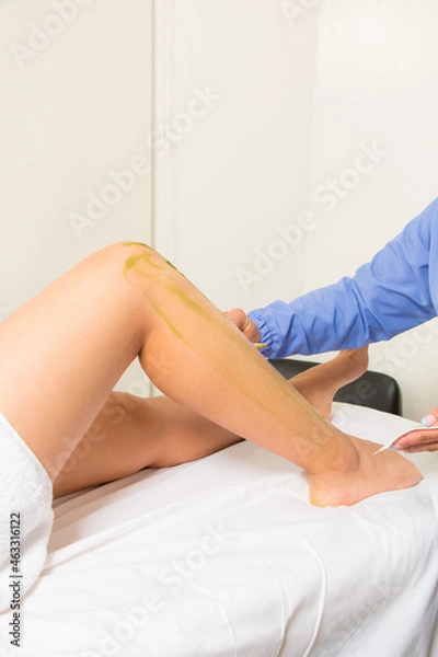 Obraz Waxing your legs: waxing procedure. Hairless legs, personal care. woman at the spa getting a body treatment