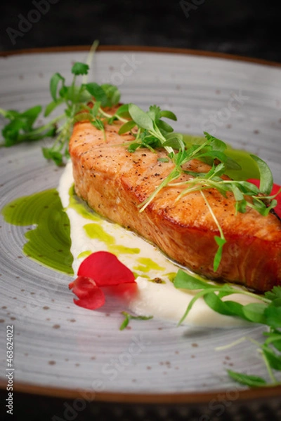 Fototapeta Grilled salmon steak with spices and a sprig of peas on a dark stone table