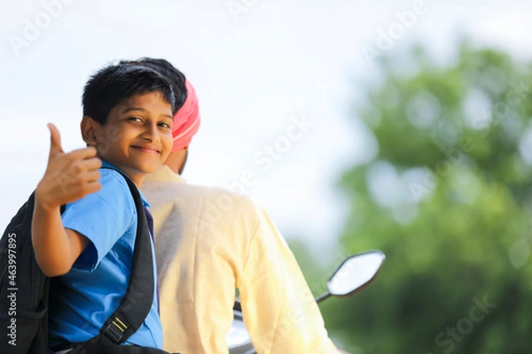 Fototapeta Young indian farmer dropping his child to school.