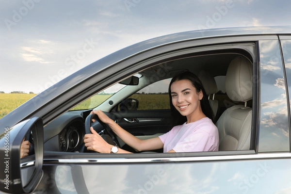 Fototapeta Beautiful young woman on driver's seat in modern car