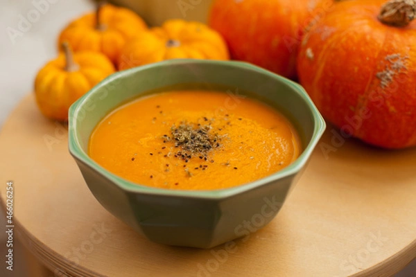 Fototapeta pumpkin soup in a bowl closeup with pumpkins around it