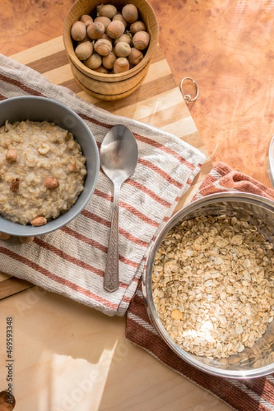 Fototapeta Healthy, dietary and nutritious oatmeal with hazelnuts in a gray plate on the table top view.