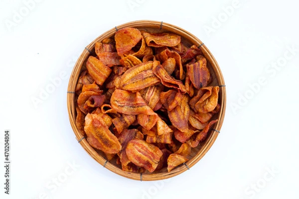 Fototapeta Banana slice chips in round bamboo basket on white background.