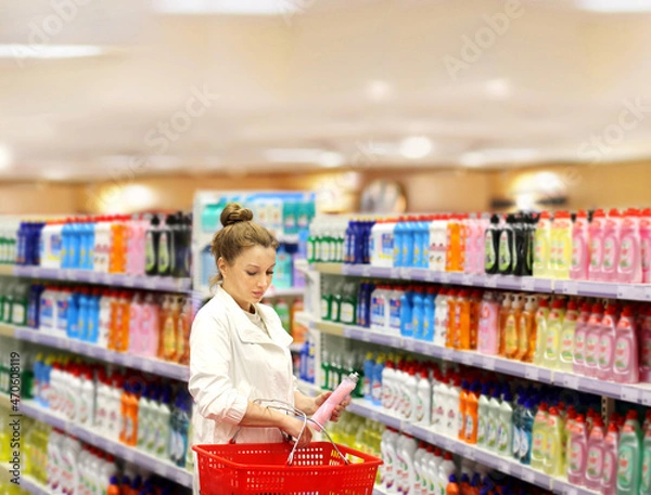 Fototapeta Woman shopping in supermarket reading product information.woman choosing laundry detergent in supermarket