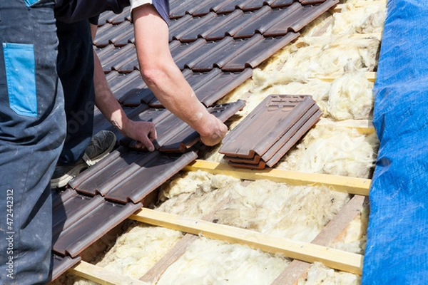 Fototapeta a roofer laying tile on the roof